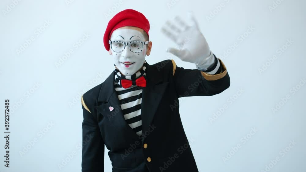 Portrait of male pantomimist looking at camera and waving hand greeting and smiling on white color background. Body language and gestures concept. Portrait of male pantomimist looking at camera and waving hand greeting and smiling on white color background. Body language and gestures concept.