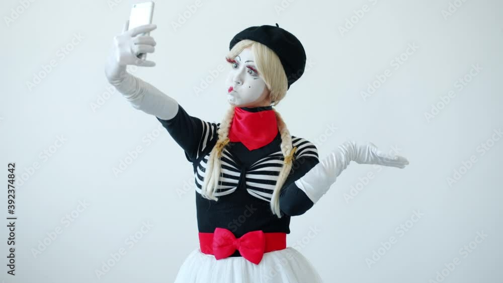 Female mime artist is taking selfie with smart phone camera posing with ...