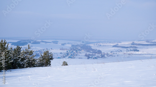 Winter countryside landscape. The village is covered with white snow. Panorama.