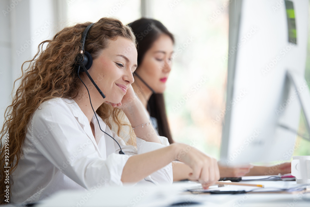 Call center worker accompanied by her team. Asian woman working in call center office as a telemarketer, customer support operator at work Call center worker accompanied by her team. Asian woman working in call center office as a telemarketer, customer support operator at work