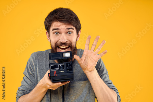 Male photographer with professional photo camera. Professional Creative approach studio yellow background