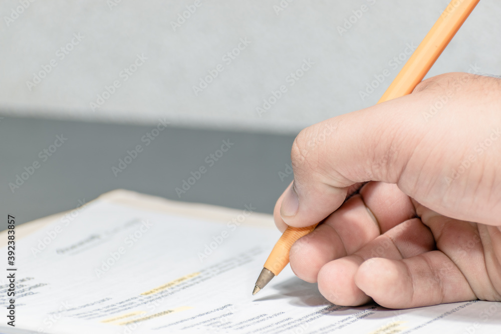 A man's hand holding a pen over a sales contract A man's hand holding a pen over a sales contract