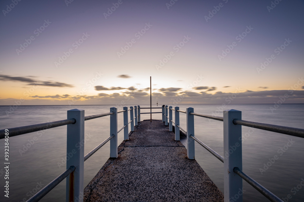 Looking out over a pier against the ocean, a purple dusk horizon sky