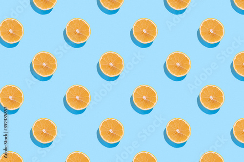 Seamless regular pattern with fresh lemons on a blue background. Hard light. Minimal summer composition.