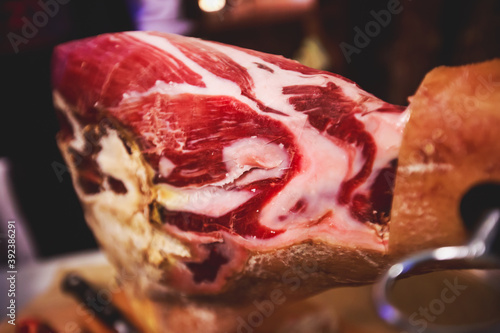 A process of slicing Hamon Jamon, traditional spanish ham on a wooden stand, slices of Parma Ham, as a part of catering on corporate party event or wedding celebration