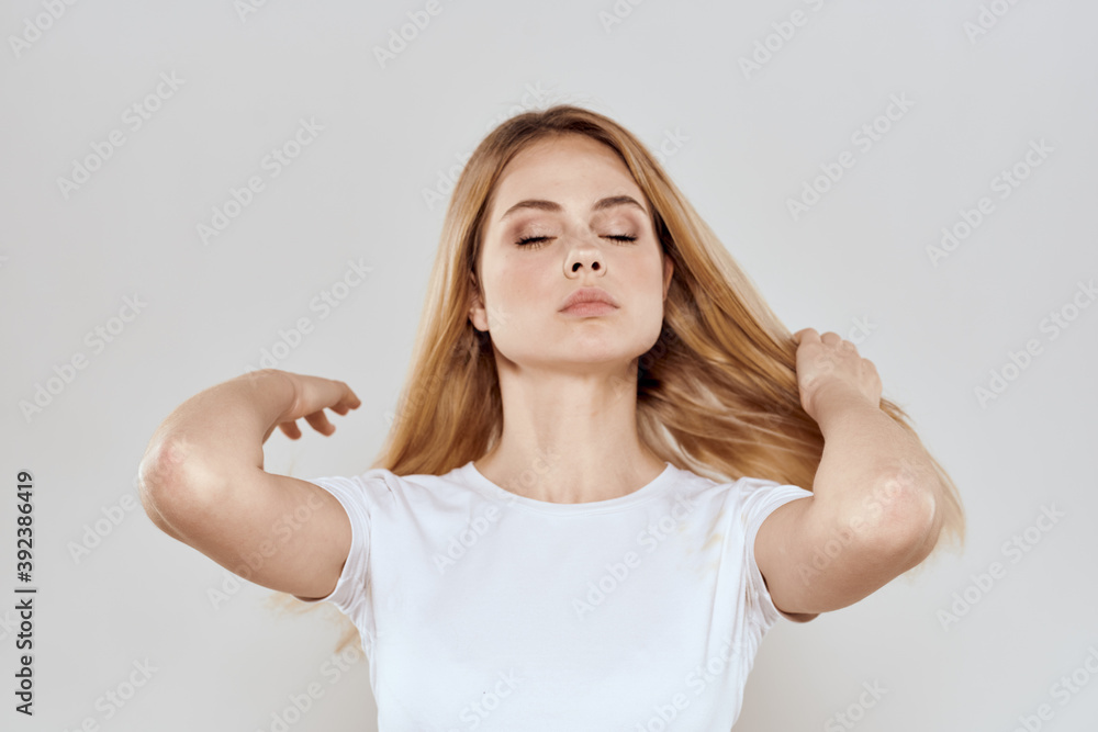 cheerful blonde in a white t-shirt gesturing with her hands light background cheerful blonde in a white t-shirt gesturing with her hands light background