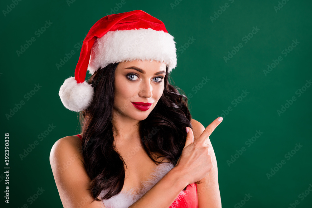 Photo of attractive snow girl indicate finger empty space wear x-mas cap isolated on green color background Photo of attractive snow girl indicate finger empty space wear x-mas cap isolated on green color background