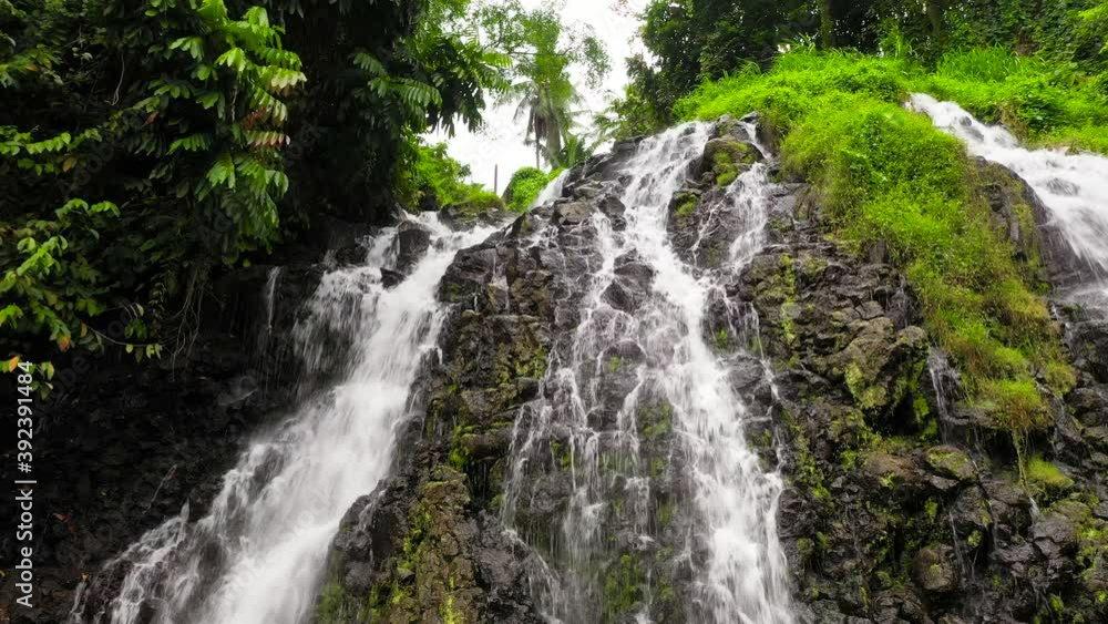 Aerial top view of jungle Waterfall in a tropical forest surrounded by green vegetation. Mimbalut Falls in mountain jungle. Philippines, Mindanao. Iligan City, Lanao del Norte.