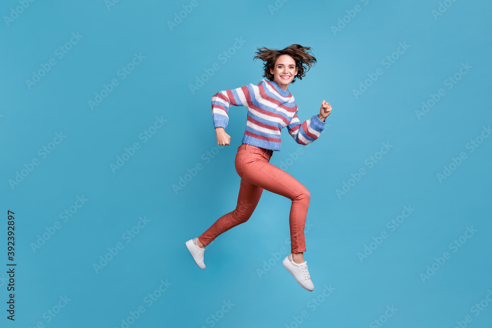 Full length body size side profile photo of jumping high hurrying up funky girl isolated on vibrant blue color background Full length body size side profile photo of jumping high hurrying up funky girl isolated on vibrant blue color background