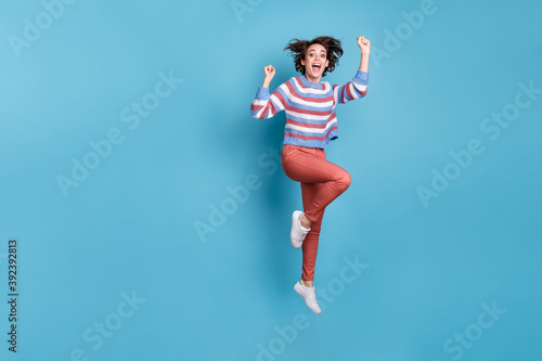 Fototapeta Naklejka Na Ścianę i Meble -  Full length body size photo of jumping high funny childish young girl keeping hands up isolated on vivid blue color background