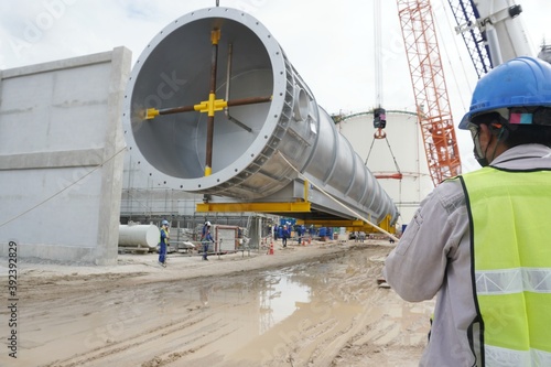 Canvastavla Worker during rope access rigger commencing high risk job to holding a safety tag line rope to control a load while crane, boom truck, truck loader is lifting transformers unit in chemical plant