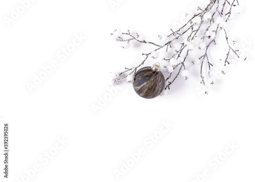 Modern winter mockup of a snow covered branch and a glass ball with creative black and gold coloring. Minimalistic template for christmas, new year, invitation, banner. Flat lay, top view, copy space.