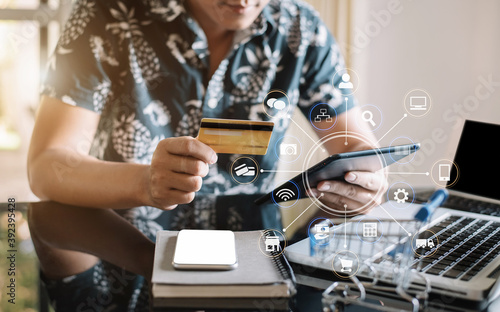 Male businessman use credit cards to conduct financial transactions through phones, tablet, and laptop.