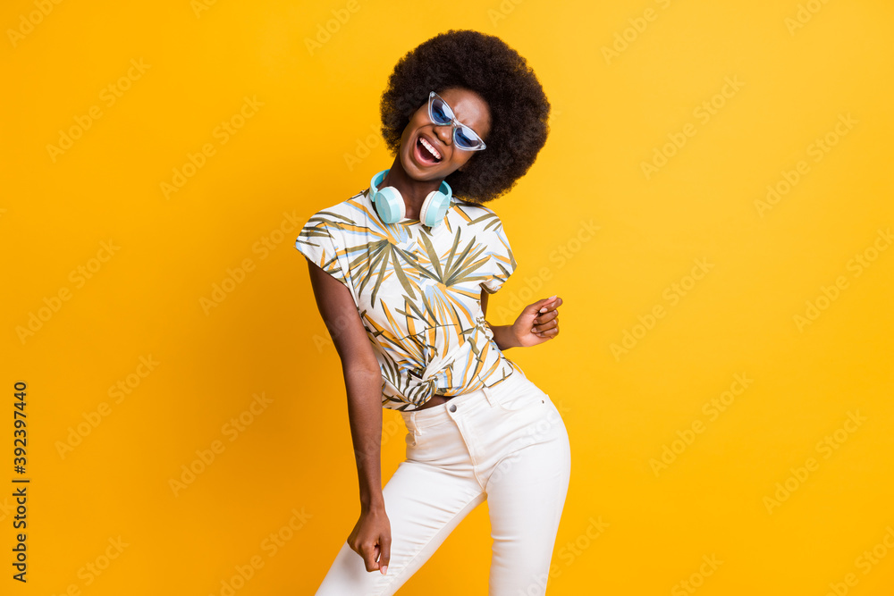Photo of pretty cute curly hair lady dancing wear headphones spectacles t-shirt trousers isolated over yellow color background