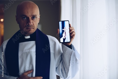 Young priest holding a mobile phone.