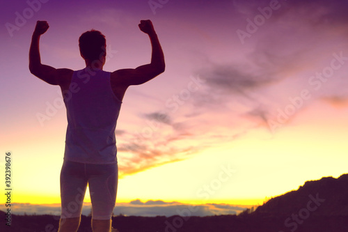 Success fit athlete man with arms up winning fitness goal challenge silhouette at dusk outdoor against mountain sunset. Life change, weight loss achievement winner person.
