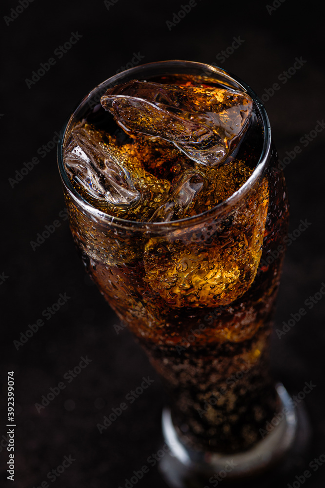 refreshing drink, cold soda with ice cubes in a tall glass on a black background refreshing drink, cold soda with ice cubes in a tall glass on a black background
