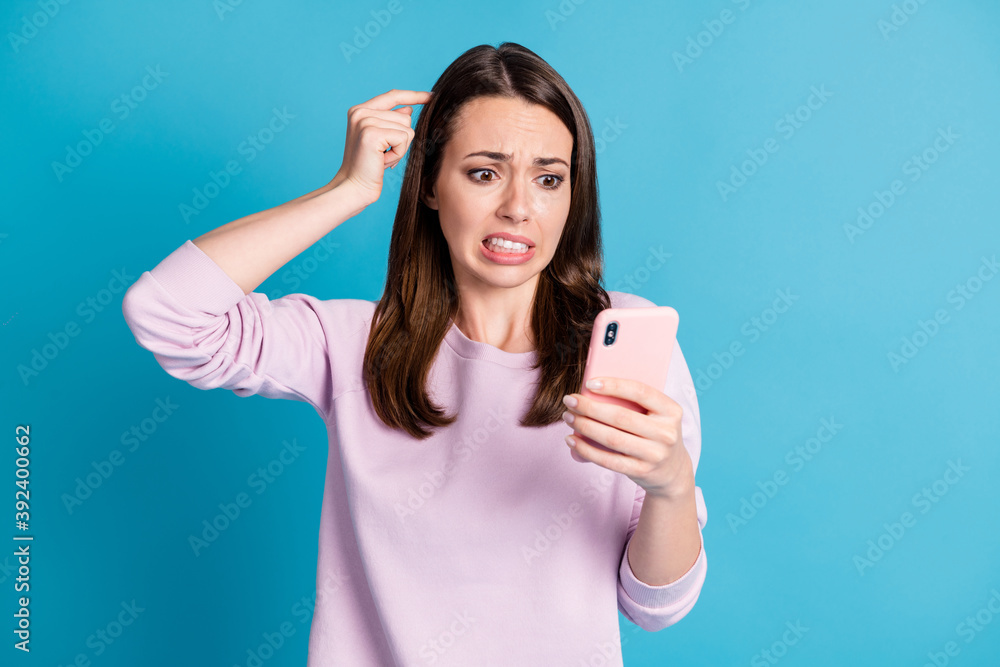 Photo of cute horrified troubled young woman hold telephone finger head city government want demolish house for building highway wear violet pullover isolated blue color background Photo of cute horrified troubled young woman hold telephone finger head city government want demolish house for building highway wear violet pullover isolated blue color background