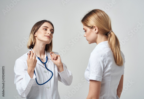 A nurse with a stethoscope and a patient on a light background