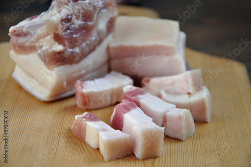 Pieces of fresh pork fat on a wooden board. Close-up