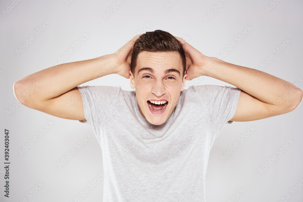 Man in a white t-shirt emotions gestures with hands close-up cropped view light background