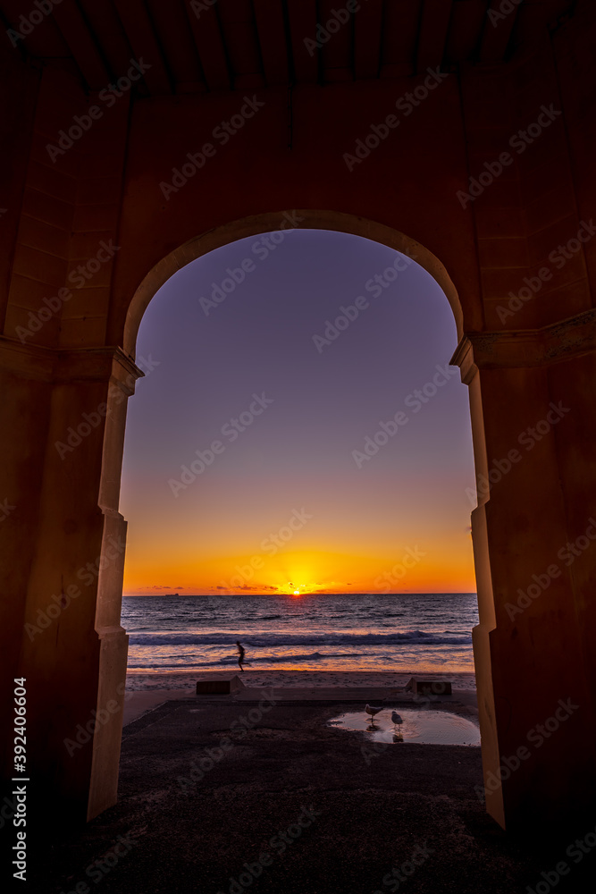 Sunset view and silhouette of the beach side from arch window 