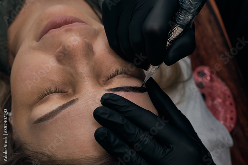 Permanent eyebrow makeup procedure. Eyebrow tattooing, process. The use of tools by a master for permanent eyebrow makeup.