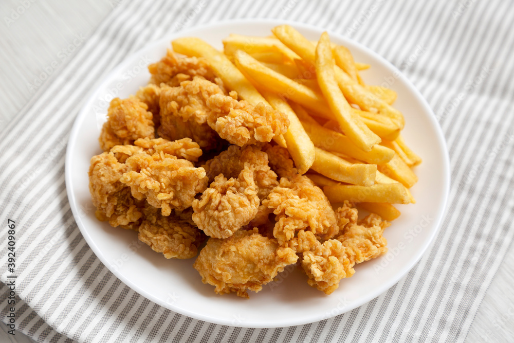 Homemade Fried Chicken Bites and French Fries on a plate, side view. Homemade Fried Chicken Bites and French Fries on a plate, side view.