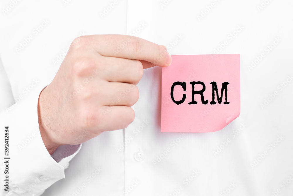 Man attaches a red sticker with text CRM overlay to his white shirt Man attaches a red sticker with text CRM overlay to his white shirt