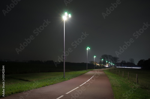 Bicycle path illuminated with green and yellow lights at night