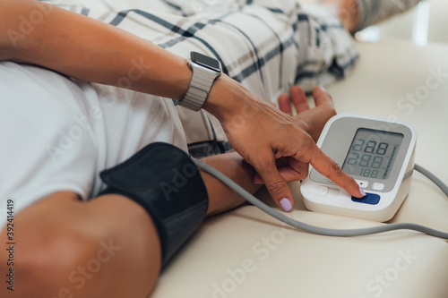 Orthostatic Blood Pressure. Woman Lying on Back and Measuring Blood Pressure on her Arm photo