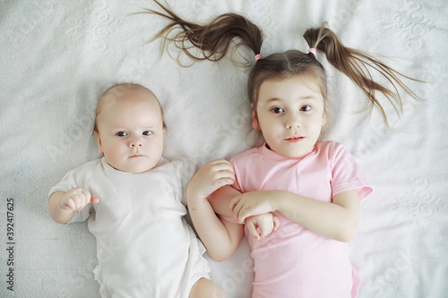 Children lie on the bed next to the newborn baby, little sister.