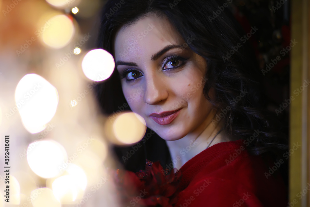 Young attractive girl wearing warm pajamas and a bedspread near the New Year tree. Christmas atmosphere. Young attractive girl wearing warm pajamas and a bedspread near the New Year tree. Christmas atmosphere.