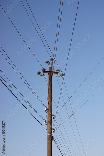 old wooden pillar with many wires blue sky background.