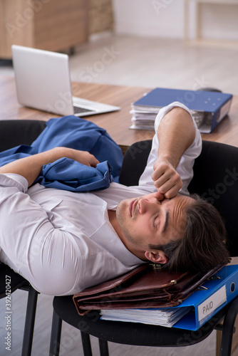 Young male employee sleeping in the office on chairs