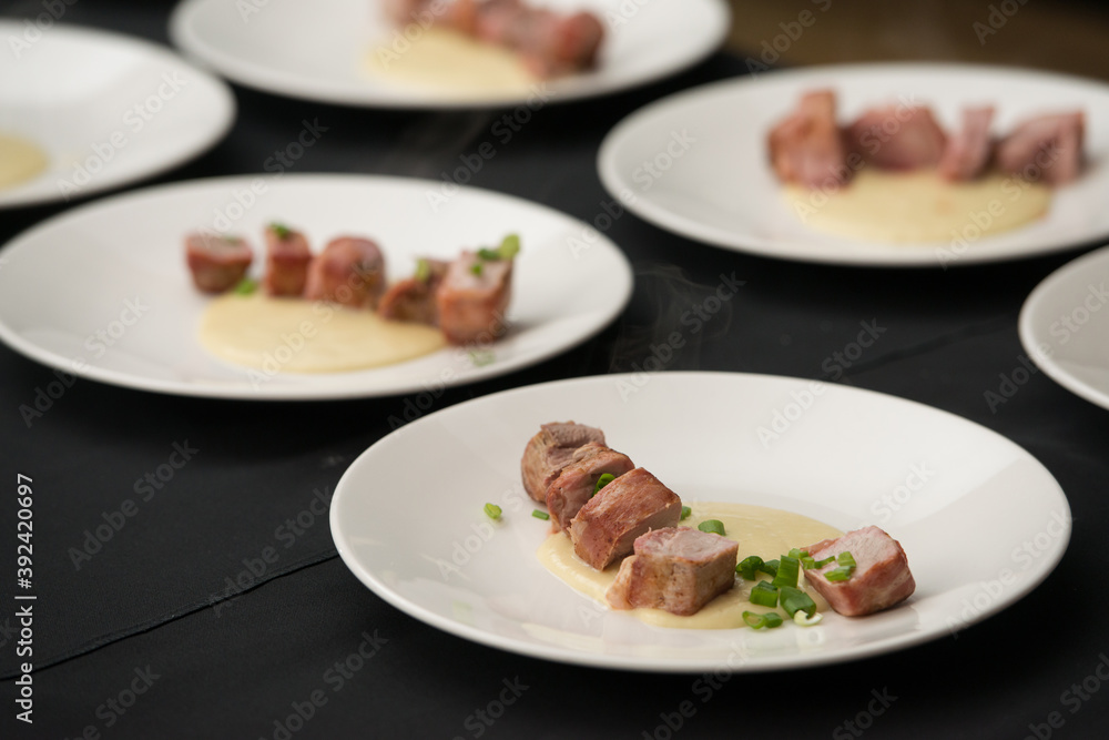 Closeup of chief serving delicious roasted pork meat wrapped in bacon. Irish traditional dish wrapped pork loin with roasted garlic Closeup of chief serving delicious roasted pork meat wrapped in bacon. Irish traditional dish wrapped pork loin with roasted garlic