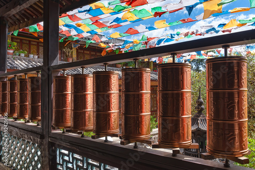 Prayer wheels in Yufeng Temple near Lijiang, China. According to the Tibetan Buddhism spinning such a wheel will have much the same meritorious effect as orally reciting the prayers photo