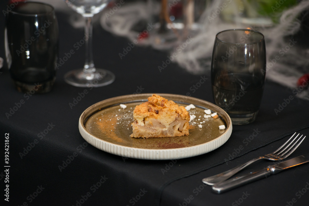 Delicious apple pie charlotte with caramel on the plate on black tablecloth Delicious apple pie charlotte with caramel on the plate on black tablecloth