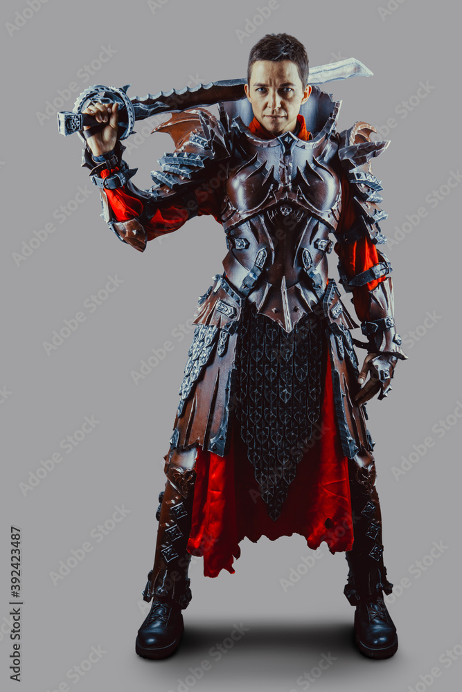 Portrait of a medieval female knight in armor with a sword in hand. Isolated over grey background. Portrait of a medieval female knight in armor with a sword in hand. Isolated over grey background.