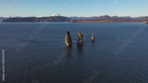 Autumn scenery, beautiful sunrise over Avacha Bay on Russia's Kamchatka Peninsula, and the famous Three Brothers Rock. The waters of the Pacific Ocean. In the background is the Avachinsky volcano.
