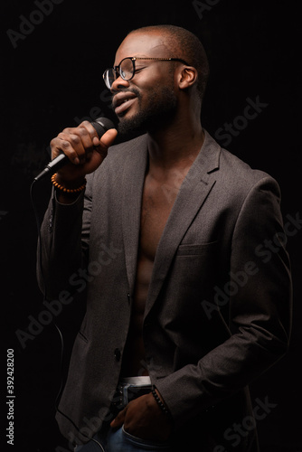 A black African American is emotionally singing into a microphone. Close-up studio portrait.