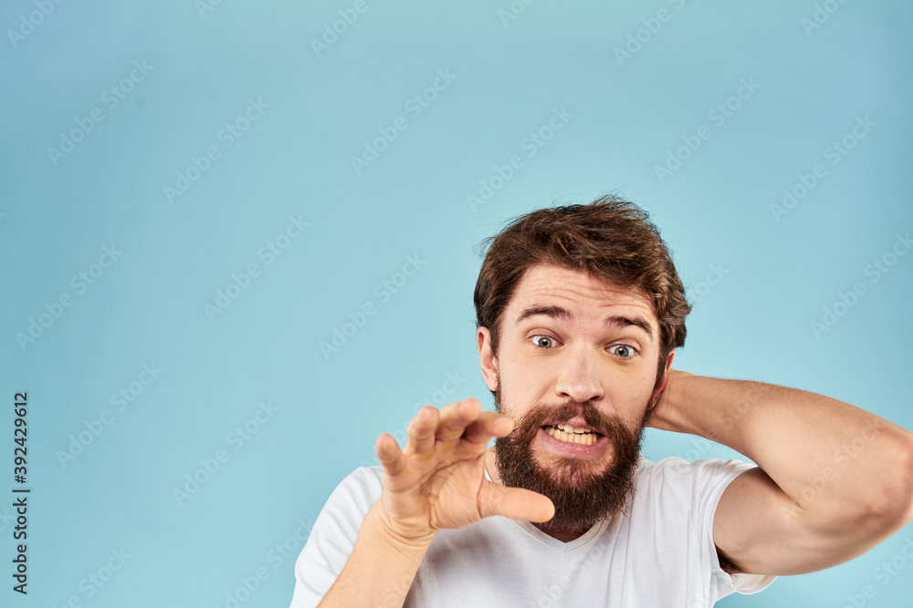 Emotional man with a beard in a white t-shirt blue background fun lifestyle Emotional man with a beard in a white t-shirt blue background fun lifestyle
