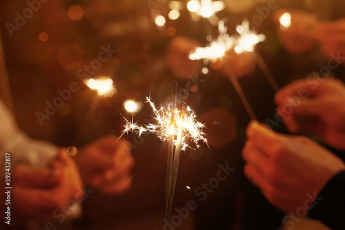 group of friends with sparklers celebrating Christmas, hands holding sparkling lights