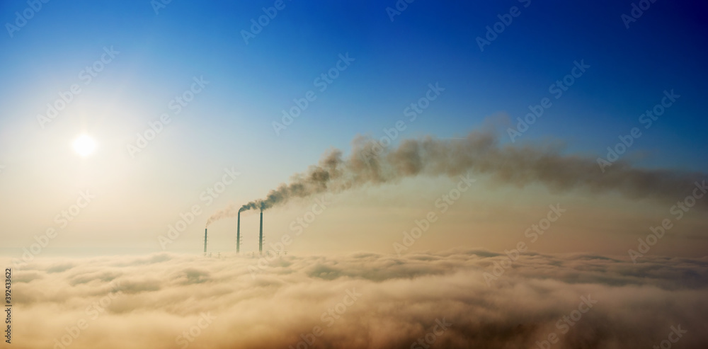 Panoramic view of thermoelectric power plant with dense smoke and colorful sky. Thermal chimneys producing smoke with toxic gases into atmosphere. Concept of energy generation, ecology and pollutions
