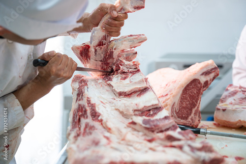 фотографія Close up butcher working separate the bone from the meat with a knife at table i