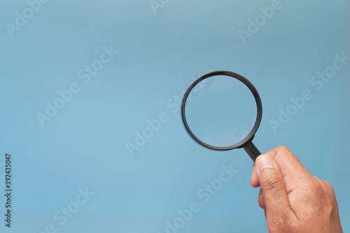 hand holding magnifying glass on color background 