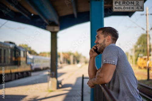 Young man using mobile phone at train station