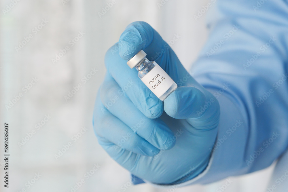 doctor hand in gloves holding coronavirus vaccine, close up