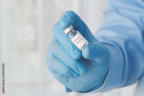 doctor hand in gloves holding coronavirus vaccine, close up