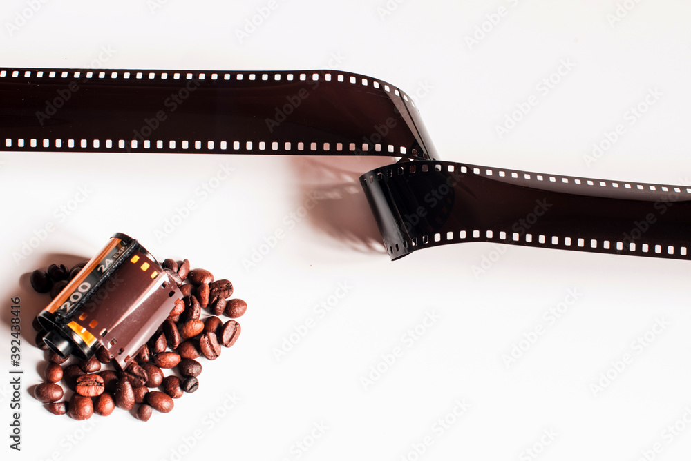Una tira de película analógica de 35mm junto a granos de café  y un rollo de película analógica de 35mm